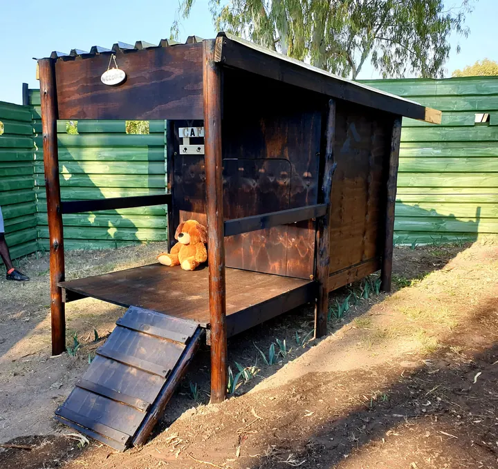 Timber K9 cabin with welcome sign and teddy bear in late-afternoon sun