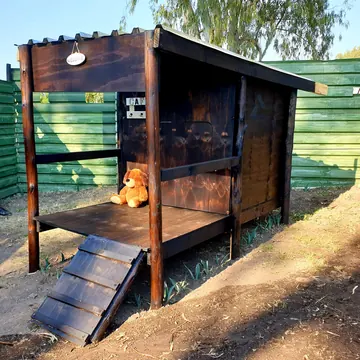 Timber K9 cabin with welcome sign and teddy bear in late-afternoon sun