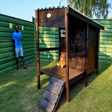 Timber K9 cabin with welcome sign and teddy bear in late-afternoon sun