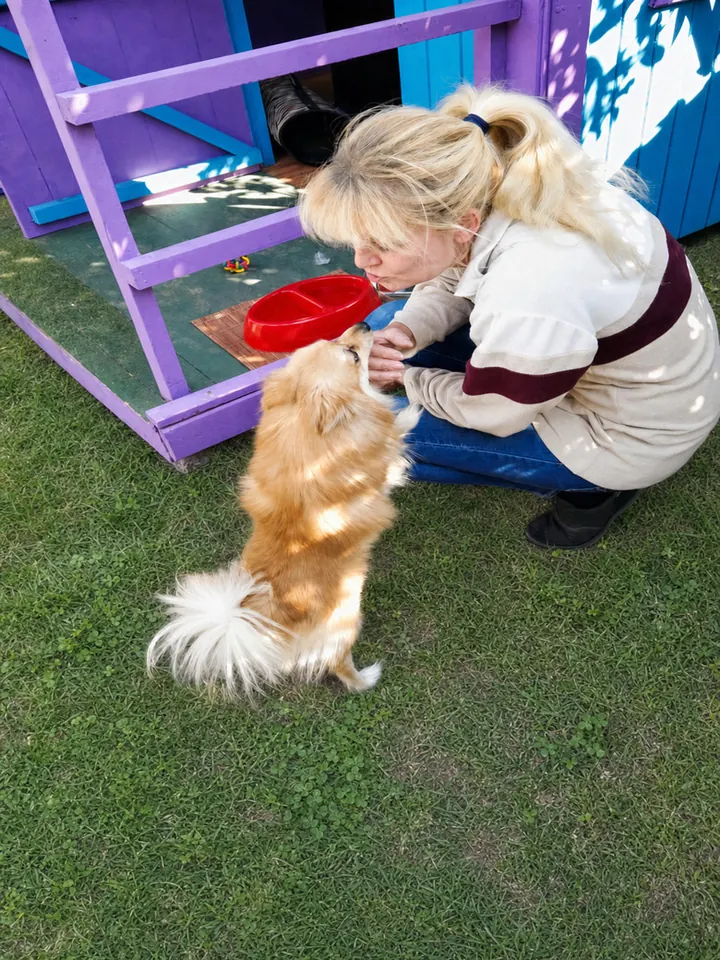 Carer sharing a nose-to-nose moment with a fluffy Pomeranian outside its cabin