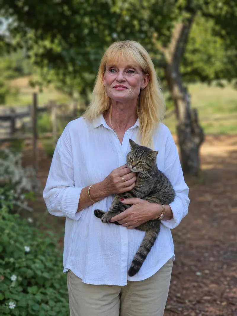Kim Praschma, owner of Purrfect Pet Hotel, holding a tabby cat in the farm garden